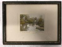 Framed color photographic print showing a natural scene with water and canoes, with visible signature and title beneath the image.