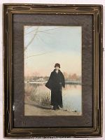 Framed vintage color photograph of a person standing beside a lake, visible aged matting and decorated frame.