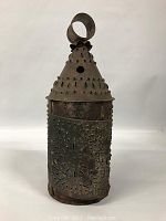 Front view of the pierced tin candle holder showing its conical top and perforated decoration.