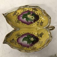 Top view of a yellow ceramic dual compartment dish with gilt and floral hand-painted decorations.