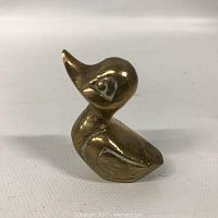 Front side view of brass duck figurine showing detailed head and wing.