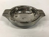 Front view of reflective metal mid century ashtray with two side rests