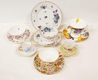 Photo of six different porcelain teacups each on their matching saucer. Various floral patterns include pink, purple, yellow, and multicolor flowers with gold rim accents.