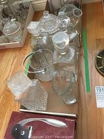 Glass and crystal decanters, ice bucket, vases, cream and sugar set arranged on cardboard surface