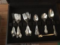 Open wooden case displaying forks and spoons in molded black velvet tray