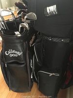 Photo showing two black golf bags standing upright, one branded Calloway Golf, with various compartments and pockets visible.
