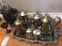 Full set arranged on a silver plate serve tray showing tea pots, cream, sugar, wine glass and tongs
