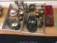 Photo showing various silver plated serve ware including cream and sugar set, cups, candle holders, salt and pepper shakers, serving utensils and a gravy boat.