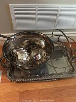 Photo showing the punch bowl containing the cups placed on one of the serving trays on the floor against a wall vent.