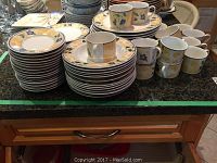 Overview of stacked plates, bowls, and cups on kitchen counter showing pattern and quantity