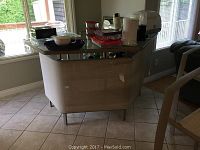 Front and side view of metal framed bar with woven fabric sides and tempered glass top showing dishes and containers on top