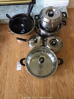 Full set of Kinox stainless steel pots and pans stacked together showing lids and handles