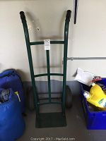 Front view of green Harper hand truck showing frame, wheels, and footplate with black rubber handles.