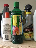 Close-up of assorted cleaning bottles including Liquafeed fertilizer and Painter's Pal cleaner with visible labels.