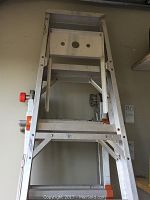 Folded aluminum Little Giant Ladder System against garage wall
