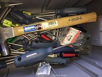Photo showing various hand tools packed inside toolbox including screwdrivers, hammer with genuine hickory handle, and some screws hardware.