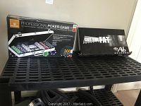 View of poker game box and Cut the Fat Ab Scissor black box on black shelf unit.