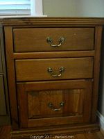 Front view of the wooden three drawer cabinet showing metal handles and drawer face details.