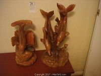 Two wood carvings on a wooden surface: a pair of carp (left), and a family of dolphins (right) showing overall size and form.