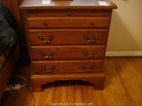 Overall front view of one nightstand showing four drawers, wood finish and hardware