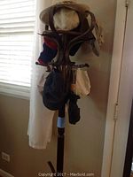 Full view of wooden coat rack with hats and bags