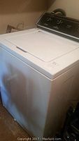 Side and top view of the white Whirlpool top-loading washing machine showing body and lid condition.
