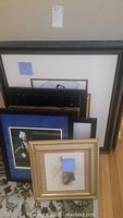 Photo showing the grouping of multiple framed pictures in a stack, with different sizes and frame styles visible.