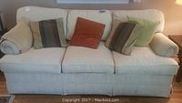 Front view of cream color sofa bed with five cushions and pillows.