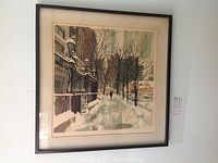 Framed Winter Rush print hung on wall showing a winter street scene with snow and a person walking in the distance.