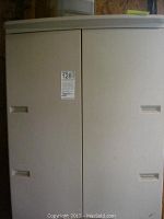 Front view of one beige plastic cabinet with double doors and handles, showing some surface marks.