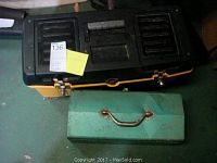 Black and yellow plastic tool chest with metal latches next to a green metal toolbox with visible rust and wear, both closed.