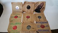 Nine vintage 78 RPM records in original paper sleeves from various labels including Victor, Columbia, Decca, Bluebird.
