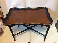 Front angle view of tray top table showing the rectangular scalloped tray surface with brown finish and black edges, supported by black bamboo-style legs with crossbars.