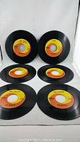 Six 45 RPM records with orange and yellow Capitol Records labels, arranged in two rows, showing front labels and vinyl condition.