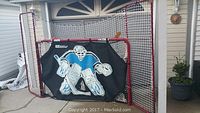 Large hockey net with extensions and goalie target in front of residential garage