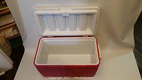 Red and white Coleman cooler with lid open showing clean, empty interior compartment