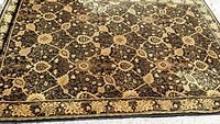 Full view of the black and gold decorative area rug showing overall pattern and border.