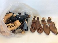 Photo showing a clear bag with multiple wooden shoe trees in various sizes and styles, plus three pairs displayed outside the bag.