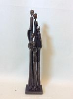 Front view of the elongated abstract iron family sculpture showing all five figures grouped together on a rectangular base.