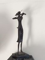 Full side profile of the metal sculpture on wood base against a plain background.