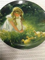Plate showing artwork of young girl in white dress with ducklings by water