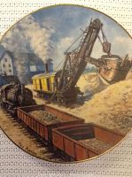 Close-up photo of Pitrun The Gravel Story plate showing detailed artwork of steam shovel and mining train with gravel piles.