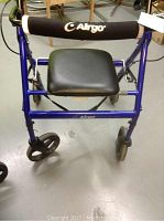 Front view of blue metal walker with black padded seat and four wheels on gray floor.