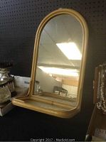 Front view of mirror with bamboo frame and built-in shelf, showing arched top and reflective glass surface.