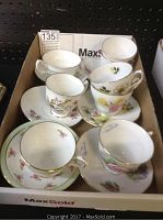 Box with 8 cups and 8 saucers showing various floral patterns, one cup near box edge with pink flower design