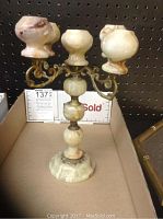 Front view of three-arm alabaster and brass-tone metal candlestick showing overall shape and condition.
