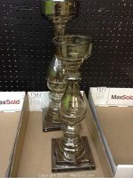 Pair of glass candle holders displayed side by side showing full length and bases on a shelf.