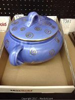 Blue ceramic covered bowl with gold spiral design and lid, showing profile view with lid and handle visible.