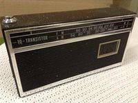 Front and slightly angled view showing the full radio including the tuner frequencies, speaker grill, and Global Transistor badge, with visible paint splatter.
