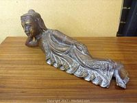 Full view of reclining Buddha statue lying on wooden surface showing body length and posture.